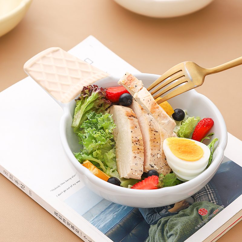 Serving bowl with fresh salad on a set table